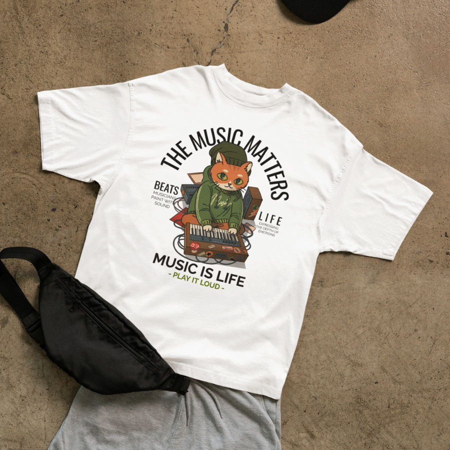 Áo thun trắng in hình mèo DJ đang chỉnh nhạc, tai nghe, hoodie và bàn mix, với slogan "The Music Matters – Music Is Life – Play It Loud", phong cách streetwear cá tính.