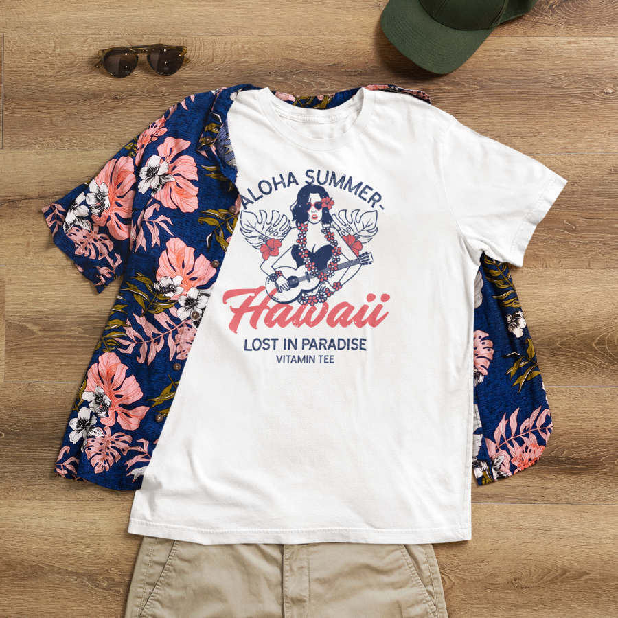 Ảnh áo thun trắng unisex in hình cô gái Hawaii chơi ukulele, dòng chữ Aloha Summer – Hawaii – Lost in Paradise, phong cách nhiệt đới mộng mơ.