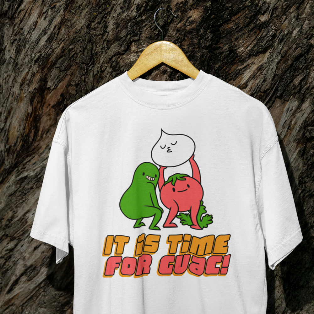 White t-shirt with cartoon characters and text 'It is time for cuac!' on a wooden hanger against a textured brown background.