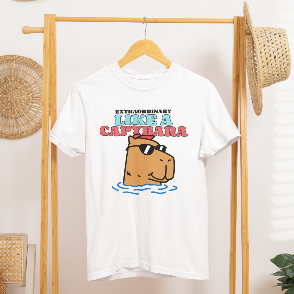 Áo thun trắng in hình capybara đeo kính râm thư giãn trong nước, dòng chữ “Like A Capybara” nổi bật, có thể tuỳ chỉnh slogan