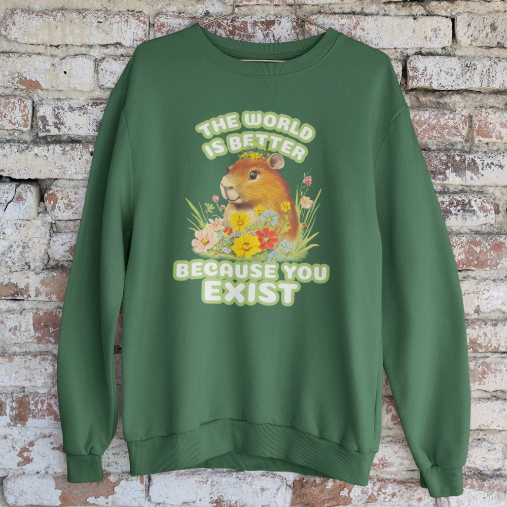 Green sweatshirt with a graphic of a guinea pig and flowers, text 'The world is better because you exist', on a brick wall background.