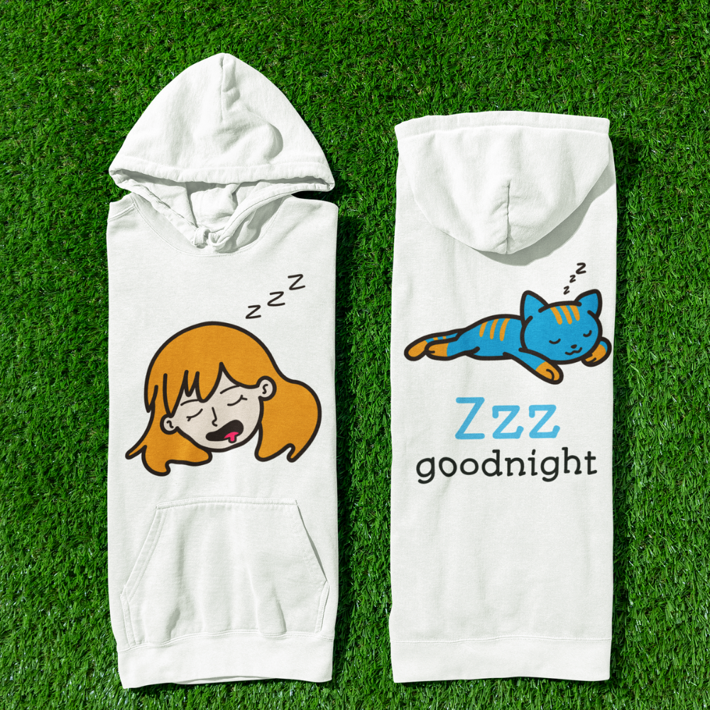 Two white hoodies with cartoon designs of a girl and a cat on a grass background
